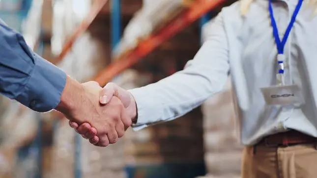 Two people shaking hands, one person has a CIMON tag